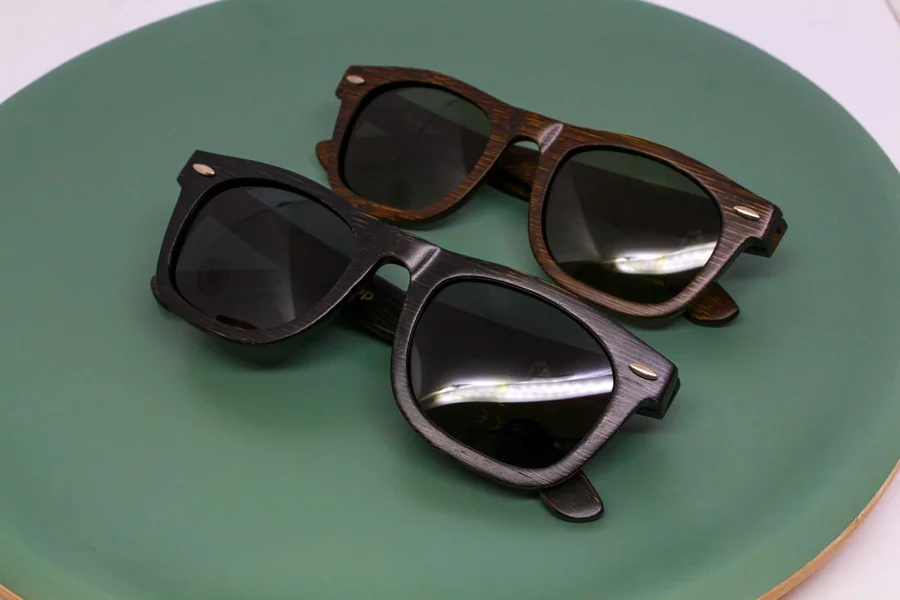 Two pairs of wooden sunglasses on a green display